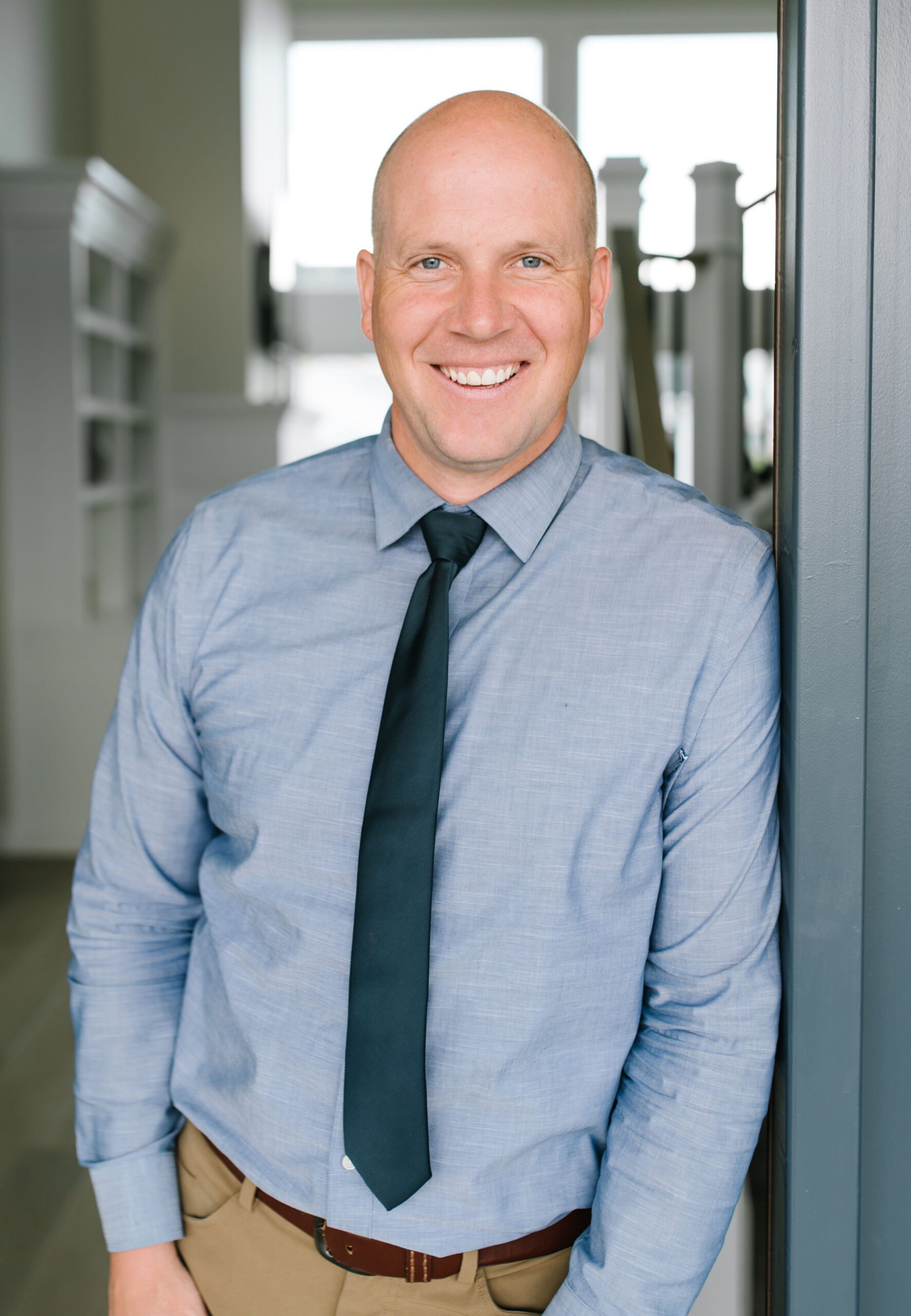 Image of Jason Knight in a blue shirt and dark tie, leaning against a doorway